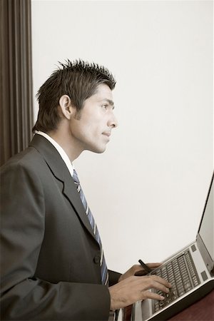 simsearch:630-01873878,k - Side profile of a businessman using a laptop on a lectern Stock Photo - Premium Royalty-Free, Code: 630-01873960