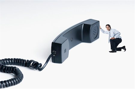 receive - Businessman listening into a telephone receiver Stock Photo - Premium Royalty-Free, Code: 630-02219388