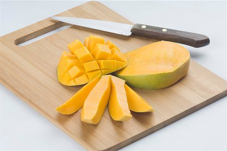 Close-up of mango slices with a knife on a cutting board Foto de stock - Sin royalties Premium, Código: 630-02219477