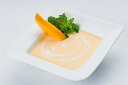 simsearch:630-02220065,k - Bowl of cream with mango slices and mint leaves Foto de stock - Sin royalties Premium, Código: 630-02219478