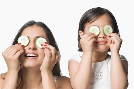 Close-up of a young woman with her daughter holding cucumber slices on their eyes Stock Photo - Premium Royalty-Free, Code: 630-02219535