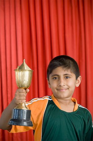 Portrait of a boy holding a trophy and smiling Stock Photo - Premium Royalty-Free, Code: 630-02219602