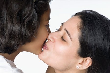 daughter kissing mother - Close-up of a mid adult woman kissing her daughter Stock Photo - Premium Royalty-Free, Code: 630-02219943