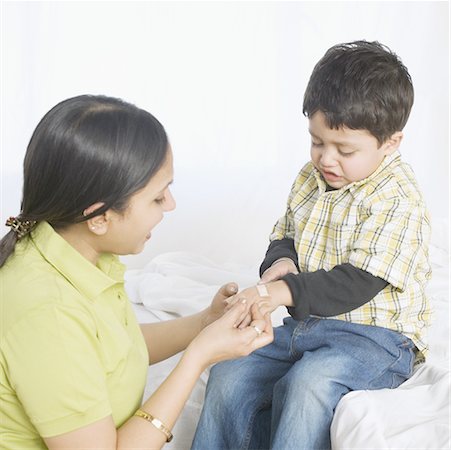 premiers soins - Gros plan d'une jeune femme, appliquer un bandage à la main de son fils Photographie de stock - Premium Libres de Droits, Code: 630-02220015