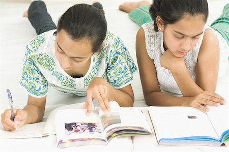 Teenage girl lying with her sister and studying Stock Photo - Premium Royalty-Free, Code: 630-02220041