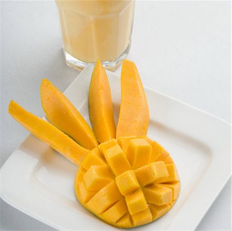 Close-up of mango slices in a plate with a glass of mango shake Stock Photo - Premium Royalty-Free, Code: 630-02220063