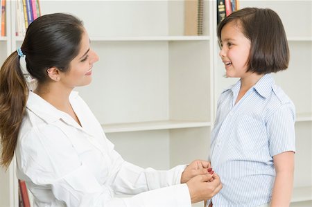 simsearch:630-02221095,k - Side profile of a young woman helping her daughter in wearing school uniform and smiling Foto de stock - Sin royalties Premium, Código: 630-02220104