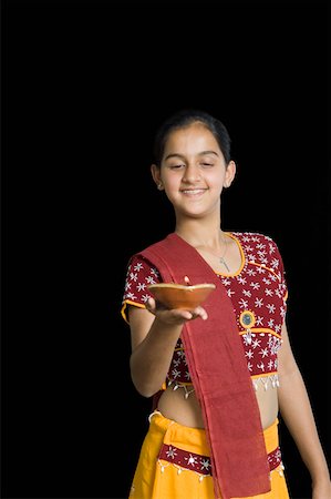 Close-up of a teenage girl holding an oil lamp and smiling Stock Photo - Premium Royalty-Free, Code: 630-02220260