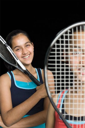 friends black background - Teenage girl holding a badminton racket with her sister Stock Photo - Premium Royalty-Free, Code: 630-02220450