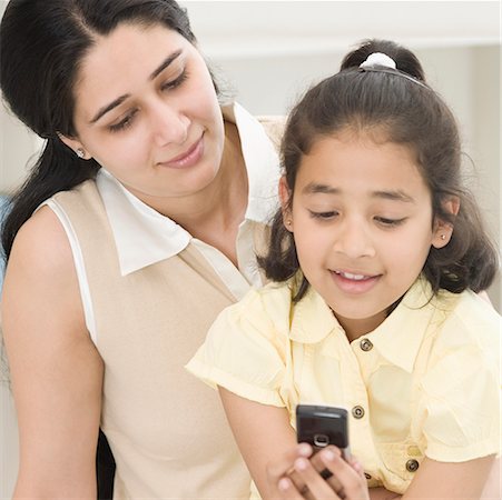 Close-up of a girl text messaging on a mobile phone and her mother looking at it Stock Photo - Premium Royalty-Free, Code: 630-02220527