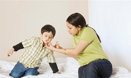 Close-up of a young woman giving medicine to her son Stock Photo - Premium Royalty-Free, Code: 630-02220612