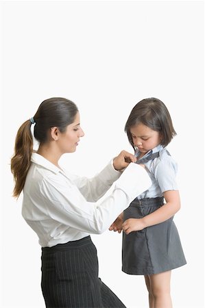 Side profile of a young woman helping her daughter in wearing school uniform Stock Photo - Premium Royalty-Free, Code: 630-02220691