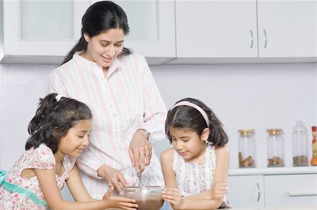 Close-up of a mid adult woman with her two daughters cooking in the kitchen Stock Photo - Premium Royalty-Free, Code: 630-02220708