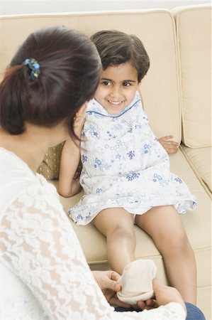 Side profile of a mid adult woman helping her daughter in wearing sock Stock Photo - Premium Royalty-Free, Code: 630-02220759