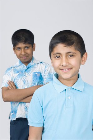 simsearch:630-02219279,k - Portrait of a boy smiling and another boy standing in the background with his arms crossed Foto de stock - Royalty Free Premium, Número: 630-02220948