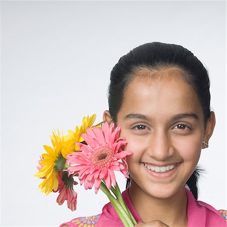 Portrait d'une jeune adolescente tenant des fleurs et souriant Photographie de stock - Premium Libres de Droits, Code: 630-02221010