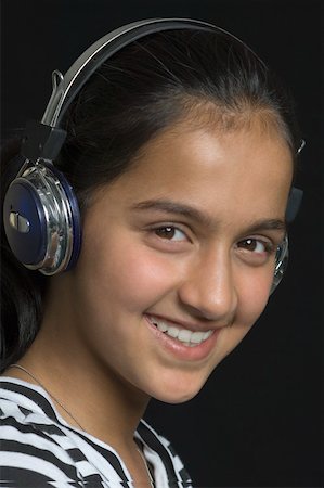 Portrait of a teenage girl listening to music with headphones and smiling Stock Photo - Premium Royalty-Free, Code: 630-02221011