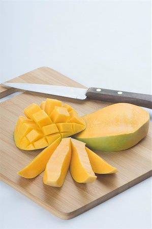 Close-up of mango slices with a knife on a cutting board Foto de stock - Sin royalties Premium, Código: 630-02221029