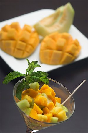 salade de fruits - Gros plan des tranches de mangue et de tranches de melon dans un verre à martini avec des feuilles de menthe Photographie de stock - Premium Libres de Droits, Code: 630-02221020