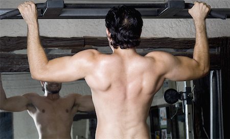 pull up man - Rear view of a young man doing chin-ups in a gym Stock Photo - Premium Royalty-Free, Code: 630-02221163