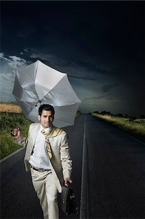 suit wind - Businessman holding an umbrella and walking on the road Foto de stock - Sin royalties Premium, Código: 630-03479327