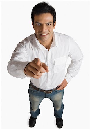 Portrait of a young man pointing and smiling Stock Photo - Premium Royalty-Free, Code: 630-03479378