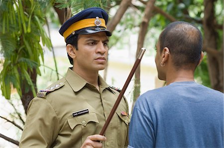 police officer - Close-up of a policeman showing a nightstick to a young man Stock Photo - Premium Royalty-Free, Code: 630-03479411