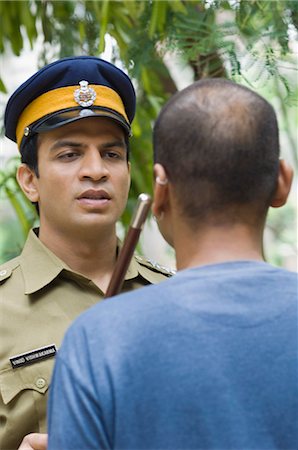 Close-up of a policeman showing a nightstick to a young man Fotografie stock - Premium Royalty-Free, Codice: 630-03479412