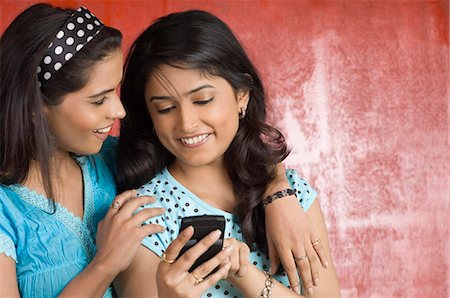 smiling student india - Young woman holding a mobile phone with her friend Stock Photo - Premium Royalty-Free, Code: 630-03479446