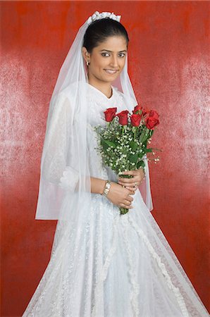 Portrait of a newlywed bride holding a bouquet of flowers and smiling Stock Photo - Premium Royalty-Free, Code: 630-03479509