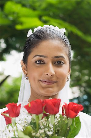 Portrait of a newlywed bride holding a bouquet of flowers and smiling Stock Photo - Premium Royalty-Free, Code: 630-03479518