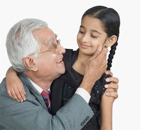 elderly man family care - Senior man hugging his granddaughter and pinching her cheek Stock Photo - Premium Royalty-Free, Code: 630-03479660