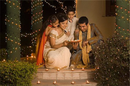 simsearch:630-03479702,k - Couple placing oil lamps on doorstep with their children Stock Photo - Premium Royalty-Free, Code: 630-03480218