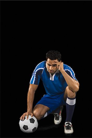 Soccer player crouching with his head in hand Stock Photo - Premium Royalty-Free, Code: 630-03480323