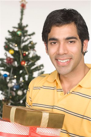 simsearch:6108-08663001,k - Portrait of a man holding Christmas presents and smiling Stock Photo - Premium Royalty-Free, Code: 630-03480386