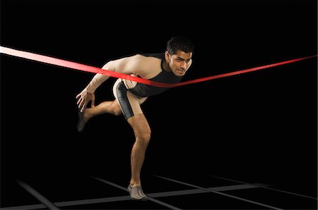 excercise black background - Athlete running through a finishing line Stock Photo - Premium Royalty-Free, Code: 630-03480382