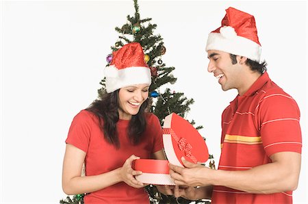 picture of man with red bow - Man giving a heart shaped Christmas present to a woman Stock Photo - Premium Royalty-Free, Code: 630-03480409