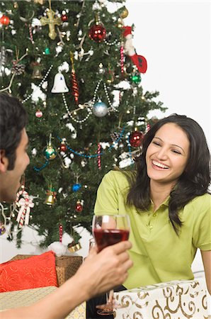 Couple drinking red wine in front of a Christmas tree and smiling Stock Photo - Premium Royalty-Free, Code: 630-03480415