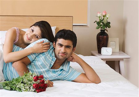 Portrait of a couple lying on the bed with bouquet of flowers Stock Photo - Premium Royalty-Free, Code: 630-03480534