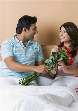 simsearch:630-03479436,k - Man giving a bouquet of flowers to his girlfriend on the bed Stock Photo - Premium Royalty-Free, Code: 630-03480547