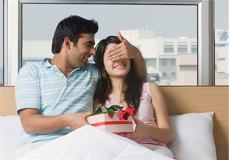 fun teenagers gifting - Man giving a present to his girlfriend on the bed Stock Photo - Premium Royalty-Free, Code: 630-03480543