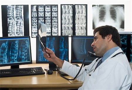 Male doctor examining an X-Ray and talking on the telephone Foto de stock - Sin royalties Premium, Código: 630-03480732