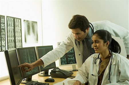 Female doctor with a male doctor examining an X-Ray report Foto de stock - Sin royalties Premium, Código: 630-03480758