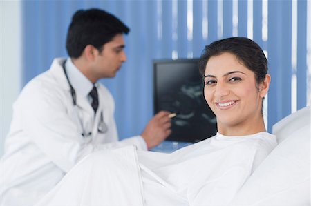 Portrait of a pregnant woman with a male doctor in a background Foto de stock - Sin royalties Premium, Código: 630-03480873