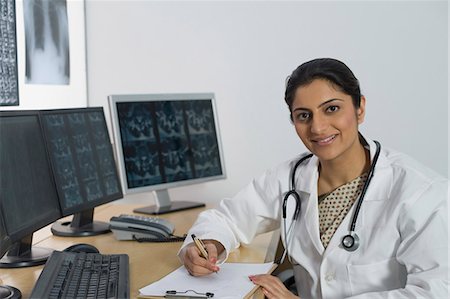 Female doctor writing a prescription and smiling Stock Photo - Premium Royalty-Free, Code: 630-03480925