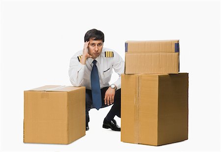 Pilot crouching near cardboard boxes and thinking Fotografie stock - Premium Royalty-Free, Codice: 630-03481135