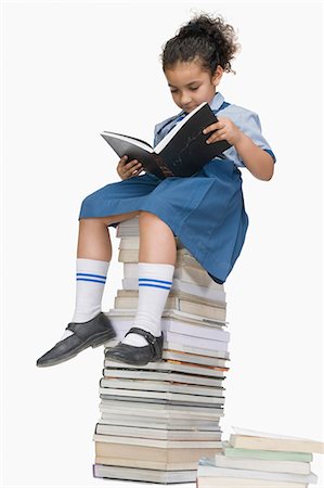 Schoolgirl reading a book on a stack of books Fotografie stock - Premium Royalty-Free, Codice: 630-03481169