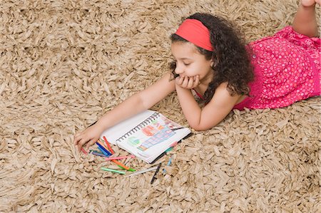 drawing a person lying down - High angle view of a girl drawing a picture Stock Photo - Premium Royalty-Free, Code: 630-03481210