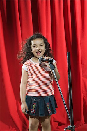 red curtains - Jeune fille jouant avec un microphone sur une scène Photographie de stock - Premium Libres de Droits, Code: 630-03481230