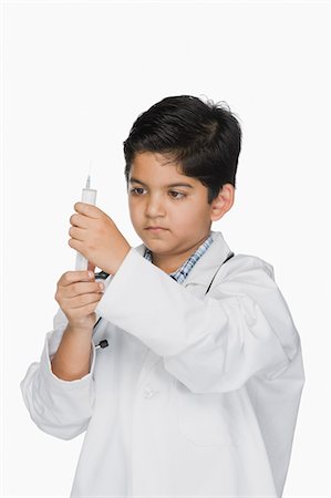 Boy imitating a doctor and holding a medical injection Stock Photo - Premium Royalty-Free, Code: 630-03481249